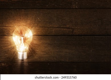 Glowing lightbulb on wooden background - Powered by Shutterstock