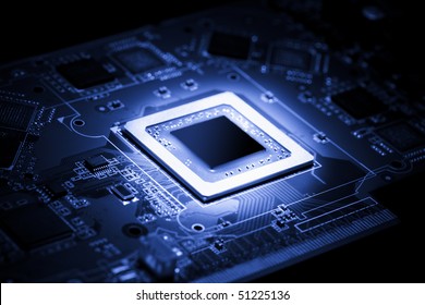 Glowing modern processor. Big illuminated graphic processor surrounding by other electrical components. Special tone image. Low aperture shot, focus on lower part of chip. - Shutterstock ID 51225136