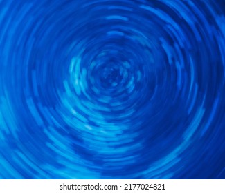 Glowing neon vortex. Blur light flare. Cyber portal. Defocused fluorescent navy blue color swirl circle motion futuristic abstract background.