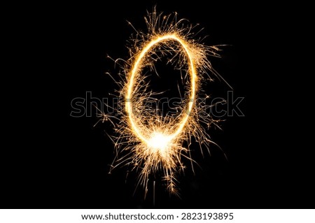 Glowing number zero created with a bright sparkling sparkler against a dark black background, perfect for New Year celebrations and festive occasions.