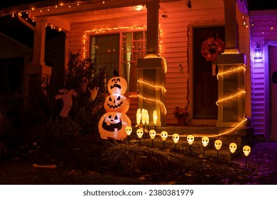 Glowing outdoor decorations with pumpkins, ghosts and orange garlands on the house porch