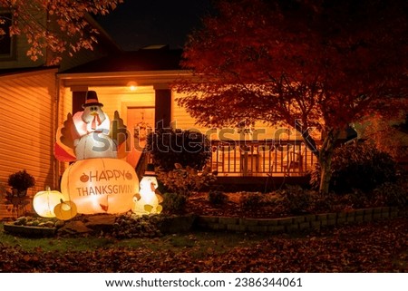 Glowing outdoor inflatable turkeys figures in the hat with inscription - Happy Thanksgiving next to the house porch