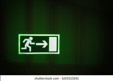 Glowing photo luminescent evacuation safety sign (emergency exit door) in the shade of the handles on the wall.