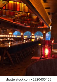 Glowing red table lantern inside a warmly lit restaurant with colourful ceiling panels