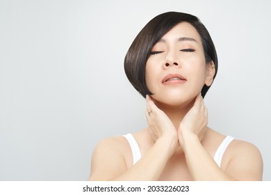Glowing skin treatment concept. Portrait of a beautiful asian woman with flawless facial, silky shinny hair relaxing touch her neck with eyes closed. K-beauty, Skincare, Clinic, Massage spa, V shape.