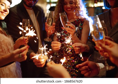 Glowing sparkles in hands. Group of happy people enjoying party with fireworks. Winter holiday, youth, lifestyle concept. - Powered by Shutterstock