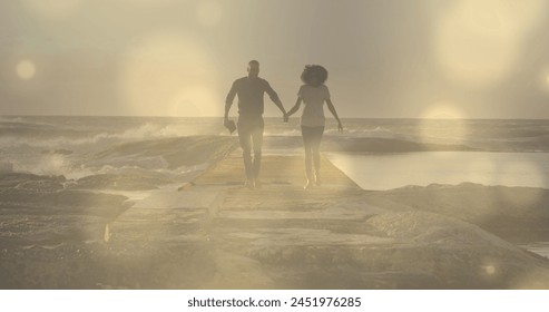 Glowing spots of light against african american couple holding hands running on the rocks. Love and relationship concept - Powered by Shutterstock