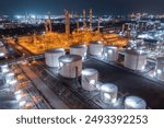 Glowing storage tanks and a labyrinth of pipes define an oil refinery under the cover of darkness, a testament to continuous industrial activity.