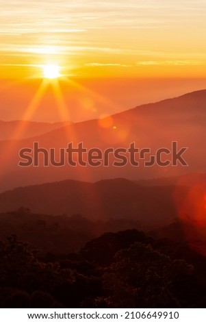 The glowing sun rising over mountains range on a cold winter day, the landscape of mountains on the morning mist. Inspiration, positive thinking concepts. Soft focus.