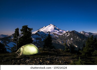 Glowing tent beneath moonlit Mount Baker, Washington state Cascades