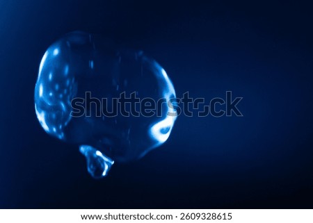 A glowing, translucent blue bubble floats against a dark blue background, with reflections and light streaks creating a futuristic and surreal effect. Includes copy space.