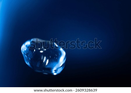 A glowing, translucent blue bubble floats against a dark blue background, with reflections and light streaks creating a futuristic and surreal effect. Includes copy space.