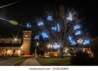 A glowing tree adorned with blue-lit doves near a historic brick church at night. Vibrant streetlights and holiday decorations enhance the festive ambiance. - Powered by Shutterstock