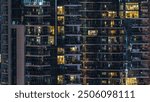 Glowing windows in multistory modern glass residential building light up at night timelapse. People in apartments. Houses illuminated at evening. Dubai Marina, UAE.