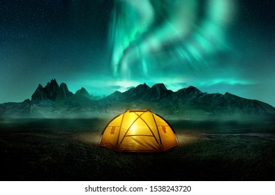 A glowing yellow camping tent under a beautiful green northern lights aurora. Travel adventure landscape background. Photo composite. - Shutterstock ID 1538243720