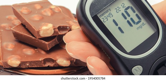 Glucometer With Sugar Level In Hand And Portion Of Chocolate On Medical Form With Results Sugar Level