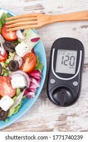 Glucose meter and fresh prepared greek salad with feta cheese and vegetables. Best healthy food for diabetics, dieting and slimming
