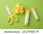 Glue, crumpled paper and scissors on green background, flat lay