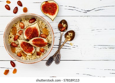 Gluten Free Amaranth And Quinoa Porridge Breakfast Bowl With Figs, Caramelized Almonds, Raisins And Honey Over Rustic White Table. Top View, Overhead, Flat Lay. Copy Space.