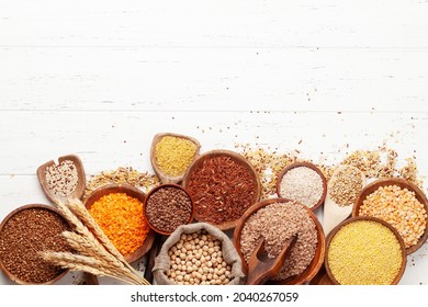 Gluten free cereals. Rice, buckwheat, corn groats, quinoa and millet in wooden bowls. Top view flat lay with copy space - Shutterstock ID 2040267059
