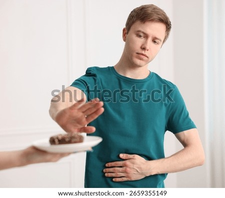 Gluten free diet. Man refusing from donut indoors, selective focus