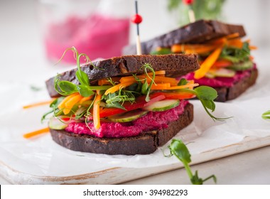 gluten free vegan sandwiches with beet hummus, raw vegetables and sprouts. soft focus