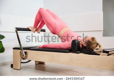 Glutes exercise on reformer machine. Mature woman during pilates workout