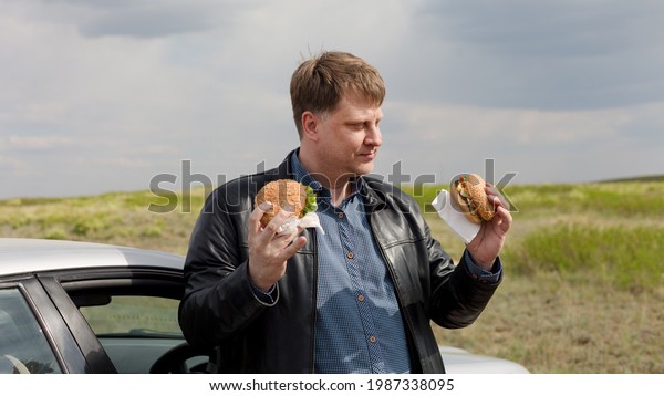 A glutton with two burgers decides which one to\
eat first.