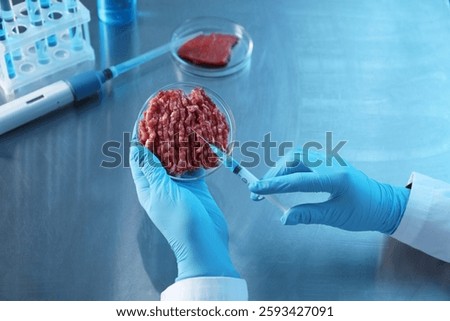 GMO concept. Scientist injecting something into minced meat at table, closeup