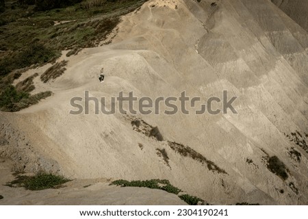 Gnajn Tuffieha, Malta - April 19, 2023: 
Landscape with a woman walking on the clay hills at Ghajn Tuffieha bay, Malta. 