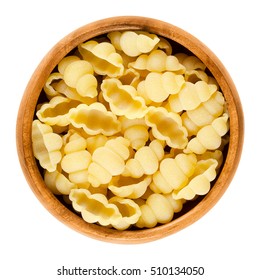 Gnocchi Pasta In Wooden Bowl. Decorative Short-cut Lobed Shells Of Italian Noodles. Uncooked Dried Durum Wheat Semolina Pasta. Isolated Macro Food Photo Over White Background.