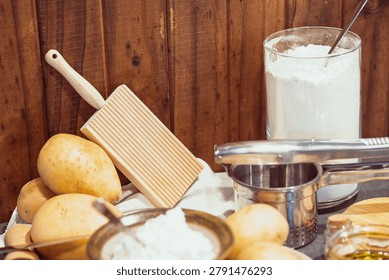 Gnocchi preparation setup featuring raw ingredients and utensils used for homemade cooking. Includes potato, flour, and egg arranged on a wooden surface, representing traditional Italian cuisine and food preparation process.