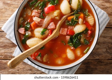 Gnocchi Soup With Sausages,, Tomato, Spinach And Vegetables Close-up In A Bowl On The Table. Horizontal Top View From Above
