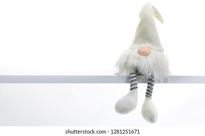 Gnome A Christmas Elf Is Relaxed And Sitting On White Shelf With Hanging Legs