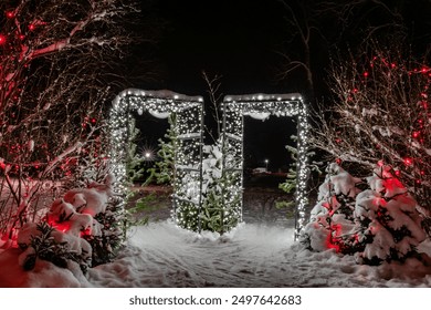 A gnome village in the Christmas mood with a snow-covered gate and Christmas trees in strings of lights in the dark of the night. - Powered by Shutterstock