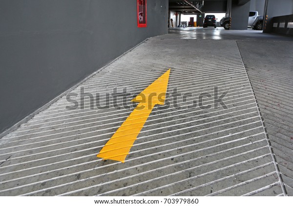 Go ahead arrow. Yellow\
Arrow signs as road markings. Arrow sign on slope floor at park\
building.