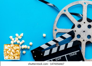 Go to the cinema with popcorn, film type and clapperboard on blue background top view mock-up
