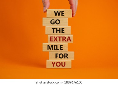 Go The Extra Mile Symbol. Wooden Blocks With Words 'We Go The Extra Mile For You'. Male Hand. Beautiful Orange Background. Business And Go The Extra Mile Concept. Copy Space.