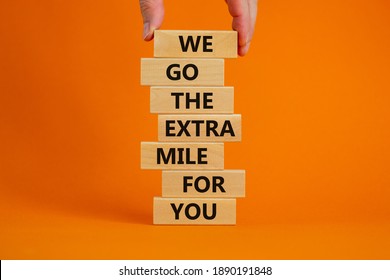 Go the extra mile symbol. Wooden blocks with words 'We go the extra mile for you'. Male hand. Beautiful orange background. Business and go the extra mile concept. Copy space. - Shutterstock ID 1890191848