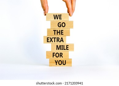 Go The Extra Mile Symbol. Wooden Blocks With Words 'We Go The Extra Mile For You'. Businessman Hand. Beautiful White Background. Business And Go The Extra Mile Concept. Copy Space.