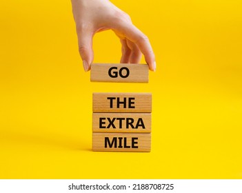 Go The Extra Mile Symbol. Wooden Blocks With Words Go The Extra Mile. Beautiful Yellow Background. Businessman Hand. Business And Go The Extra Mile Concept. Copy Space.