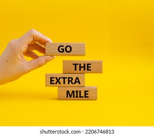 Go The Extra Mile Symbol. Wooden Blocks With Words Go The Extra Mile. Beautiful Yellow Background. Businessman Hand. Business And Go The Extra Mile Concept. Copy Space.