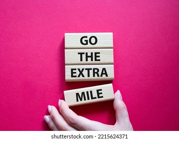 Go The Extra Mile Symbol. Wooden Blocks With Words Go The Extra Mile. Beautiful Red Background. Businessman Hand. Business And Go The Extra Mile Concept. Copy Space.