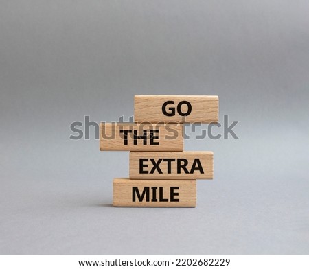 Go the extra mile symbol. Wooden blocks with words Go the extra mile. Beautiful grey background. Business and Go the extra mile concept. Copy space.