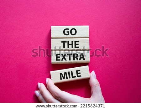 Go the extra mile symbol. Wooden blocks with words Go the extra mile. Beautiful red background. Businessman hand. Business and Go the extra mile concept. Copy space.
