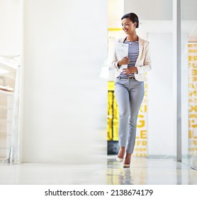 Go Getter On The Move. Shot Of A Young Woman Walking Down An Office Hallway.