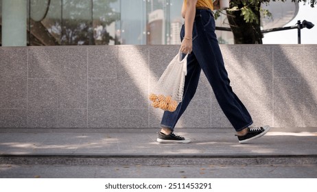 Go green Gen Z asia young woman relax step walk in city life carrying fruit reuse eco mesh bag save the earth world care. Close up floor leg foot shoe reduce issues net zero waste hope the way forward - Powered by Shutterstock