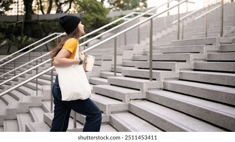 Go green Gen Z woman asia young people carrying eco tote bag reuse step walk up stairs in city life save the earth planet world care. Reduce garbage issues asian hope net zero waste the way forward. - Powered by Shutterstock