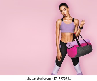 Go to gym! Sporty girl in fashionable sportswear with sports bag on pink background. Sports and healthy lifestyle