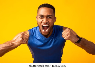 Go For It. Emotional Afro Sports Guy Celebrating Goal, Making Winner Gesture With Clenched Fists, Screaming, Yellow Wall